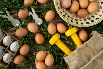 Gym dumbbells, Easter eggs, boxwood branches and bunny decorations. Healthy diet choice concept. Fitness workout, sport training flat lay composition.