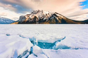 Wall Mural - Frozen Lake Minnewanka with rocky mountains and cracked ice from the lake in winter at Banff national park