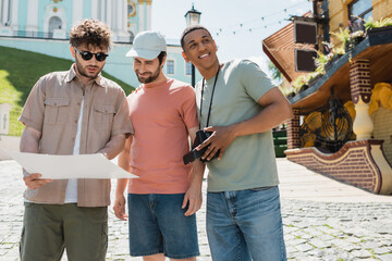 Wall Mural - young tour guide showing city map to multiethnic travelers on andrews descent in kyiv.