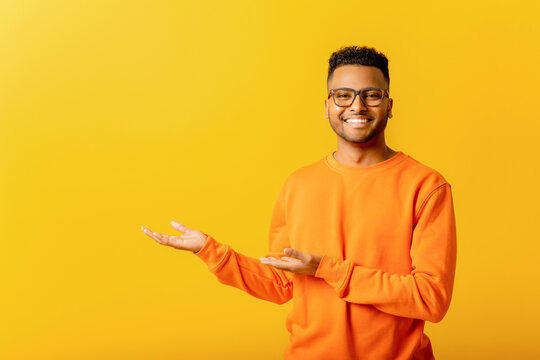 cheerful indian man pointing at copy space with his palms, empty place for idea presentation, produc