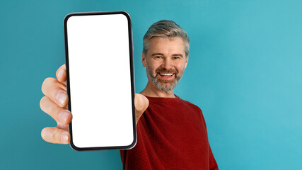 Excited handsome middle aged man showing phone with white screen