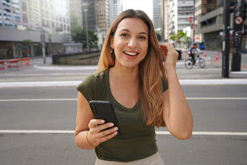 Canvas Print - Authentic people outdoors. Self-confident girl with phone looking at camera in empty metropolis in the morning on summer.