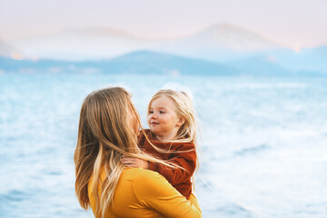 Wall Mural - Child daughter and mother family vacations lifestyle travel together mom hugging kid walking outdoor at the lake Mothers day holiday