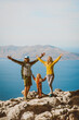 © EVERST - Family hiking in Greece parents with child travel outdoor mother and father raised hands active summer vacations healthy lifestyle eco tourism in Rhodes island mountain top