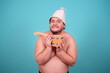 © Denis - Funny fat man in a hat and with a sauna ladle. Blue background. Taking a shower.