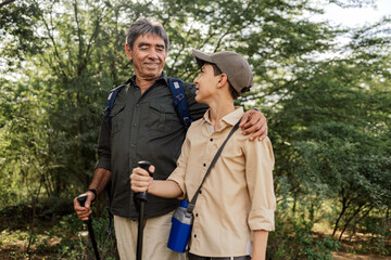 Active senior hiking in the woods with his grandson