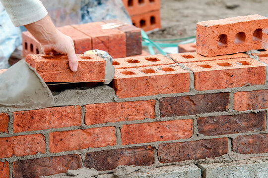 hard working bricklayer lays bricks on cement mix on construction site. fight housing crisis by buil