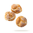 © BarTa - Cream puffs, pastry from choux covered sugar powder closeup falling flying isolated on white