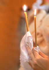 a girl holds a lighted candle in her hands, a religious tradition, a symbol of the Christian faith, a wax candle burns with an even flame, blow out a candle, a smoke from an extinguished wick 