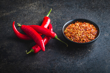 Wall Mural - Dry chili pepper flakes. Crushed red peppers in bowl on black table.