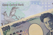 A one thousand yen note from Japan paired with money from Qatar