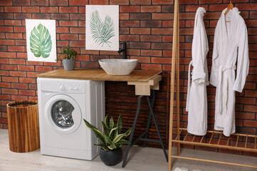 Wall Mural - Washing machine and wooden rack with terry bathrobes indoors. Laundry room interior design