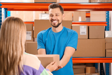 Wall Mural - Worker giving parcel to woman at post office, space for text