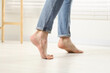 © New Africa - Barefoot man walking on white parquet indoors, closeup. Heated floor