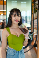 Wall Mural - Portrait of beautiful sexy asian woman Wearing a green strapless dress and jean skirt in a cafe