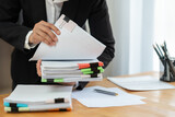 Fototapeta  - Businesswoman in black suit working at desk with documents preparation, searching, sifting through information related to financial, earnings, taxes of company to prepare for meeting in office.