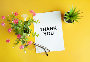 thank you concept on the note paper on yellow background, along side with potted plants
