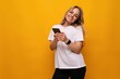 © Ivan Traimak - a girl with a gadget in her hands makes an order on the Internet on a yellow background
