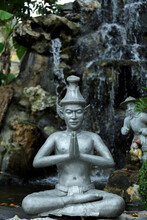 Buddha Statue Against Artificial Waterfall