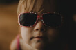 © Cavan Images - Close-up portrait of cute baby girl in sunglasses at home