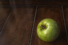 High Angle Close-up Of Wet Granny Smith Apple On Wooden Table