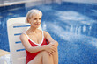 © luengo_ua - Happy vacation. Senior woman in red swimwear on the sunlounger near the swimming pool.