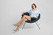 © boomeart - Elegant senior woman in mini skirt and white sits in armchair