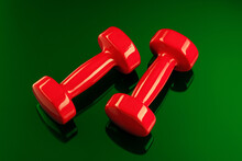 A Pair Of Red Dumbbells Is Reflected In A Green Glass Surface. View From Above.