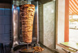 Rotating spit for making traditional turkish street food Doner Kebab on table in a street food shop