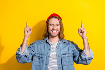 Poster - Photo of cheerful positive man wear denim jacket pointing two fingers up empty space isolated yellow color background