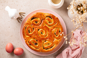 Sticker - Top view of beautiful Easter yeast roll cake or bread with custard pastry cream and chocolate. Easter colored eggs, white bird statue. Beige and pink table background.