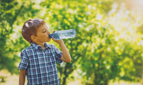 Fototapete - Cute boy drinking a bottle of pure water in nature.