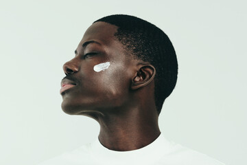 Wall Mural - Young black man taking care of his skin with nourishing face cream