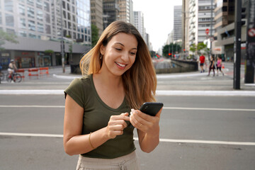 Canvas Print - Smiling girl using smartphone on Paulista Avenue, Sao Paulo, Brazil