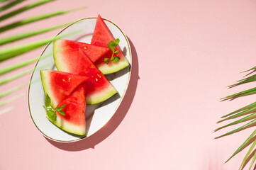 Wall Mural - Slices of fresh watermelon in a plate, top view, pink background with copy space. Summer foods.