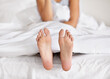 © C.M./peopleimages.com - Wiggling toes of wakefulness. a pair of womans feet poking out from under the sheets of a bed.