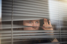 Blond Man Peeking Through Window Blinds