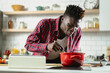 © JustLife - African man preparing food in modern kitchen. Handsome chef cooking pasta.