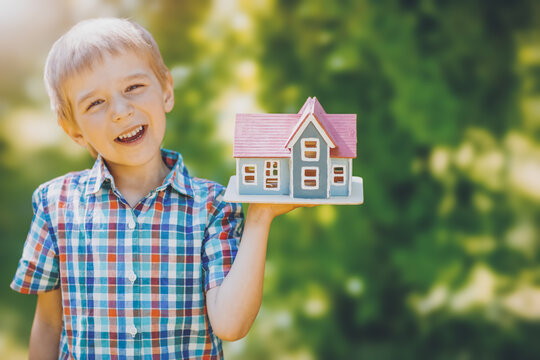 Fototapete - Little child holding in his hand a model of the house.