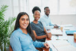 © Meeko Media - Portrait of diverse team sitting in a row at boardroom table, young women