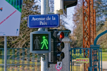 Green light of pedestrian traffic light with street name sign Avenue de la Paix at Swiss City of Geneva on a sunny winter day. Photo taken March 5th, 2023, Geneva, Switzerland.