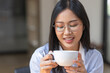 © David - Beautiful young Asian woman working on laptop computer while sitting at the plan office space after working hours, Asian woman drinking coffee