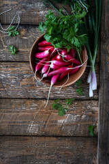 Wall Mural - Long breakfast radishes and fresh springtime herbs on wood board