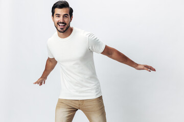 Poster - Fashion man jumping and running in a white t-shirt and jeans, smile with teeth joy on a white isolated background, fashionable clothing style, copy space, space for text