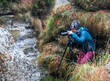 nature photography - Man with camera and tripod stationed on the bank of a river