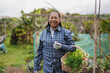 © Sabrina - Happy senior african woman holding basket with fresh vegetables in the garden - Harvest concept