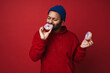 © Drobot Dean - Indian man eating sweet donuts isolated over red background