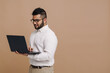 © Drobot Dean - Smiling indian man working on laptop isolated over beige background