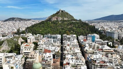 Wall Mural - Aerial drone cinematic video of Athens cityscape and iconic chapel of Saint George on top of Lycabettus hill with beautiful deep blue sky, Athens, Attica, Greece