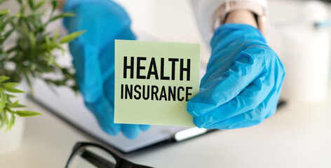 Doctor woman holding card in hand with text Health Insurance on the table.